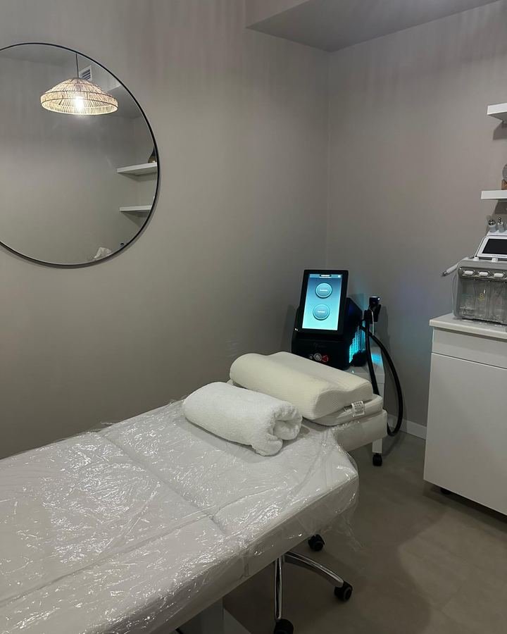 Gabinete de depilação a laser do Amalfi Beauty Hair, com marquesa branca, toalhas dobradas e equipamento de laser.